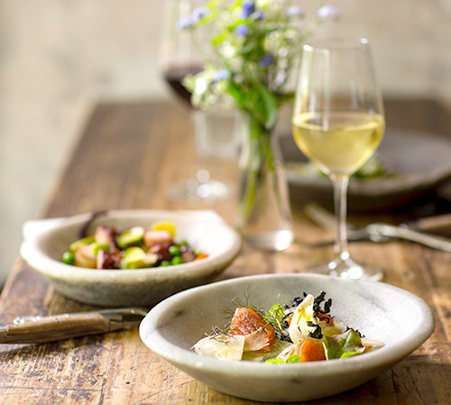Two plates of salad & glasses of wine on wooden table