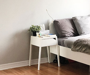 bedroom with grey sheets and a white nightstand