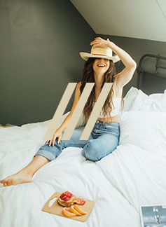 woman wearing a cowboy hat and sitting in bed