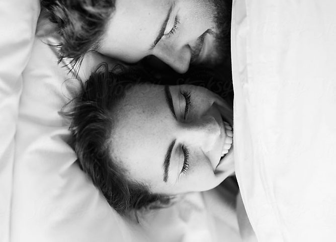 couple smiling and laying in bed